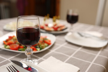 Festively laid table with glasses of red wine.