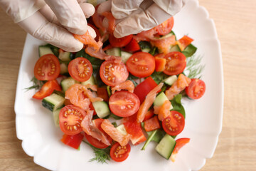 Pieces of salmon are added to a vegetable salad. Preparation of vegetable salad