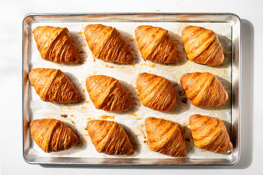 Tray of baked croissants on white plaster background
