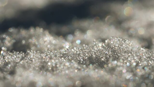 Close-up view of snow crystals that are glistening in the light. The focus is on
