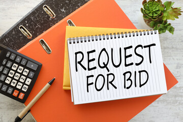 Request For Bid on dark office background. two bright folders on the table.text on paper