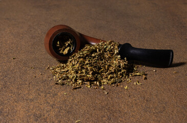 A filled smoking pipe and a handful of tobacco.