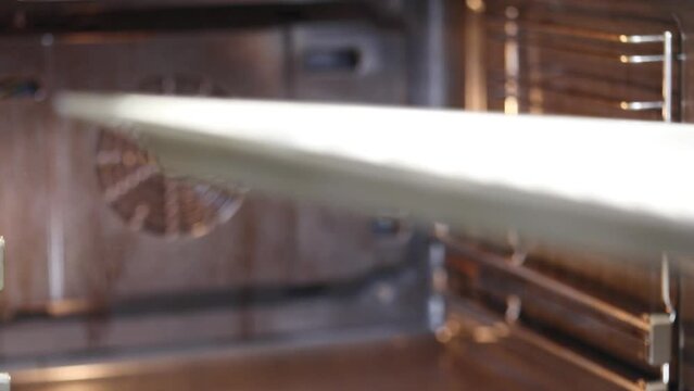 Putting baking sheet with whipped protein cake into hot oven, slow motion