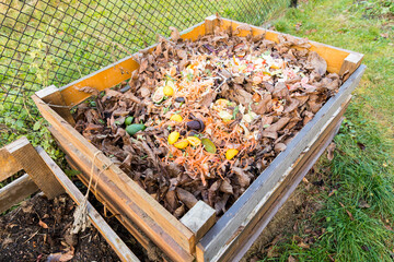 A composter made of wooden boards filled with bio-waste from the kitchen.