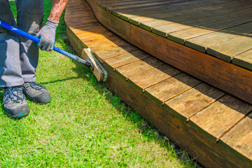 Terrace cleaning. Renovating a gray terrace using a hard scrub brush and green gel for renovating faded, gray boards - an alternative to washing with a high-pressure washer - 730356920