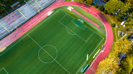 Aerial view of a football field with athletic track. Top view of red running track and green soccer pitch. © Stefano Tammaro