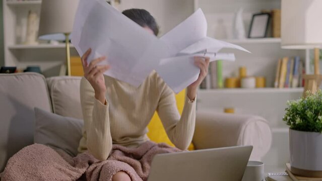 Stressed young Asian woman holding her head feeling headache and thinking how to find money to pay credit card debt and all bills,asian woman feeling stressed calculating mothly expenses at home