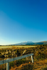 Fototapeta na wymiar Rustic White Fence Leading to Snow-Capped Mountain in the Distance - New Zealand Travel North Highlands Tongariro National Park