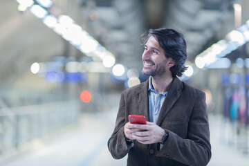 View of young man using a smartphone inside a subway - metro station with a blurred view landscape in the background. High quality video. Texting, talking on the phone. 