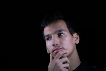 Portrait for teenager with thinking expression in dark and light studio