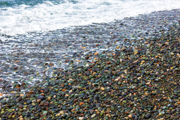 Colorful pebbles on a beach with waves approaching the shoreline