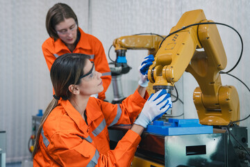 Student engineer Assembling Robotic Arm with computer in Technology Workshop. Service Engineer Holding Robot Controller and Checking Robotic Arm Welding Hardware.