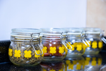 kitchen spices and ingredients jars on black and white background with reflection
