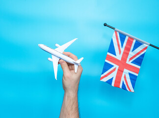 British flag in a man's hand. Travel concept with airplane in hands to Great Britain with flag on...