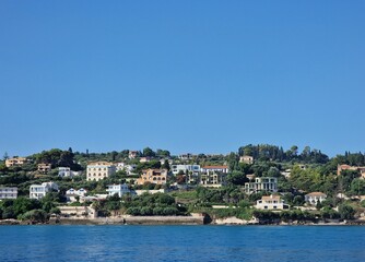 A row of colorful houses on a hill overlooking the ocean. A row of brightly colored houses clings to a hillside overlooking the ocean.
The houses are all different colors, from blue to green to yellow