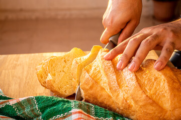 hands holding the knife and cutting the bread into slices to be served