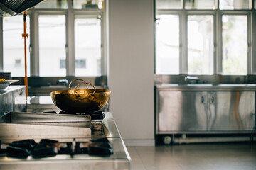 A shiny metal bowl adorns the stove in a professional kitchen of a modern restaurant. Clean...