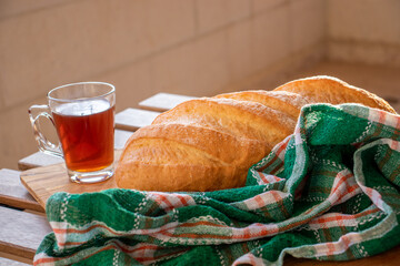 Bread on wooden table ready to be served and cup of tea on white background