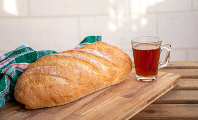 Bread on wooden table ready to be served and cup of tea on white background