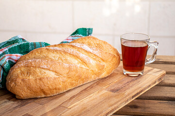 Bread on wooden table ready to be served and cup of tea on white background