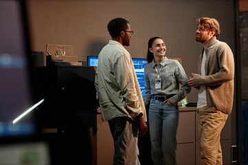 Multiethnic group of three people standing in office and talking while working at night