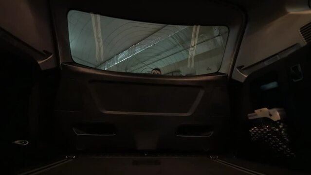 Man in black clothes closes car boot in underground garage