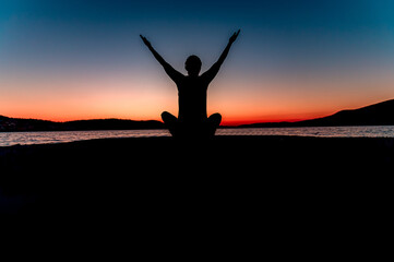 Kobieta ćwicząca jogę o zachodzie słońca nad morzem - obrazy, fototapety, plakaty