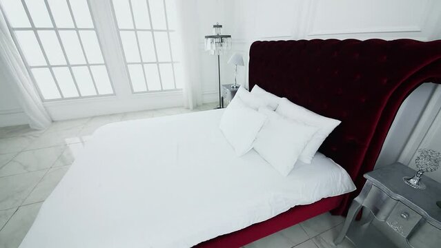 White interior with bed and flowers near large window in photo studio