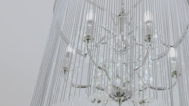 Crystal lustre with beads hangs on white ceiling in photo studio