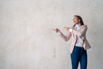 Portrait of a beautiful young woman pointing towards copy space against a background in a studio.