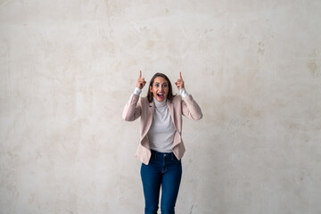 Studio shot of a excited young woman pointing towards copy space.