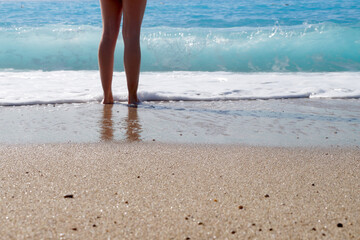 bare feet of a girl in sea water on the beach
