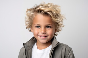 Portrait of a cute little boy with blond curly hair in a gray jacket.