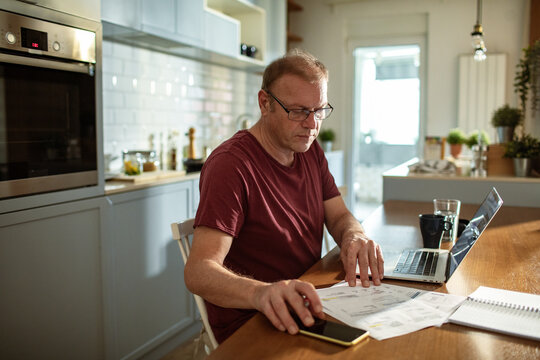 Stressed man going over bills at home