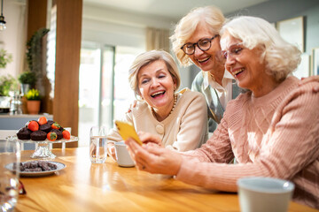 Group of senior women using smartphone together at home