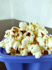 A bowl full of popcorn on the wooden table.