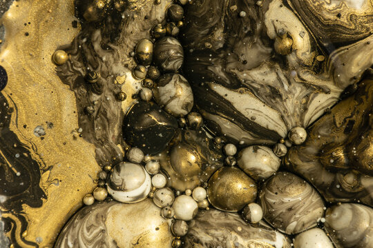 An elegant display of gold and black ink swirling with a luxurious marbled pattern, dotted with bubbles to create a mesmerizing abstract