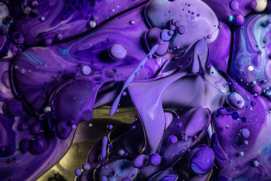 A mesmerizing scene of deep purple and blue inks swirling together with glossy bubbles in a dark, liquid fantasy