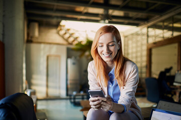 Smiling young woman using smartphone in office