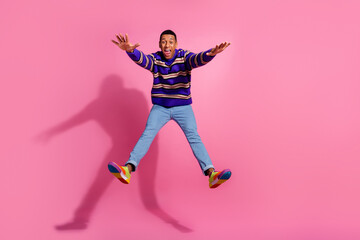 Fototapeta na wymiar Full body photo of attractive young man jumping stretch hands legs wear trendy purple striped clothes isolated on pink color background