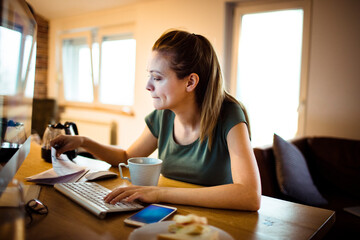 Focused woman working from home office with papers and coffee