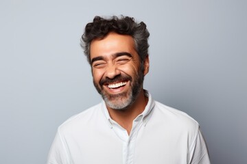 Portrait of a happy man laughing and looking at camera against grey background