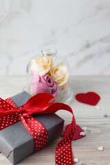 Valentine's Day concept: gift box with red ribbon, red hearts and pink paper envelope on a light background. flat lay