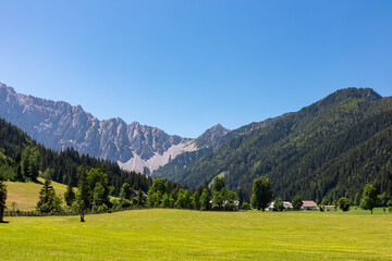 Lush green alpine meadow of Maerchenwiese with panoramic view of Karawanks mountains in Carinthia, Austria. Looking at majestic summit of Vertatscha and Hochstuhl. Remote alpine landscape in Bodental
