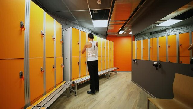 Man walks in dressing room, open locker and then close it before leave