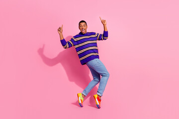 Fototapeta na wymiar Full length photo of impressed excited man wear striped sweater having fun showing two fingers up empty space isolated pink color background