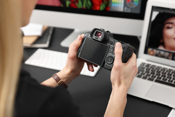 Professional photographer with digital camera at table indoors, closeup