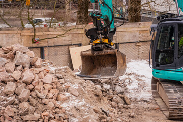 Construction rubble excavator bucket in work during winter construction project