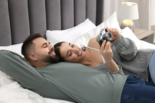 Happy young couple with camera on bed