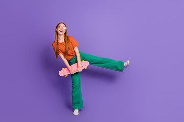 Photo of funky cheerful girl wear trendy outfit hold penny board have fun enjoy summer season isolated on purple color background